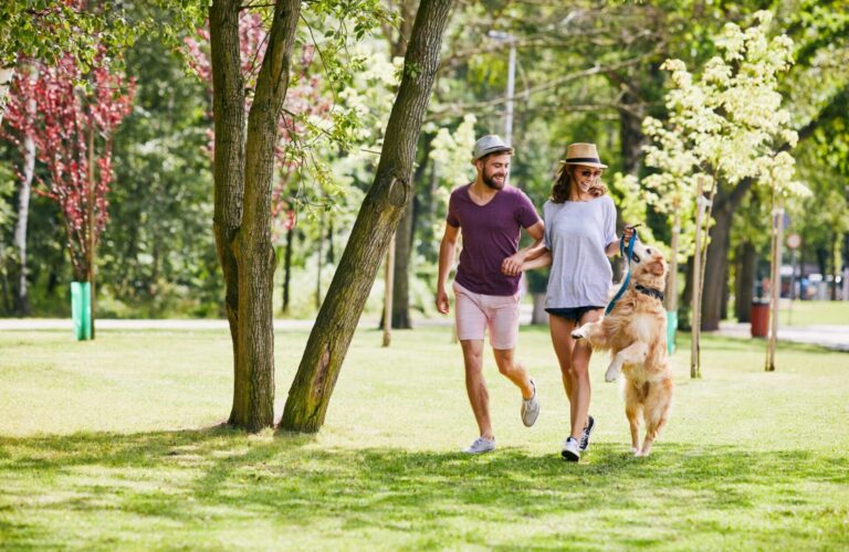 Young couple running and playing with their dog outdoors in the morning